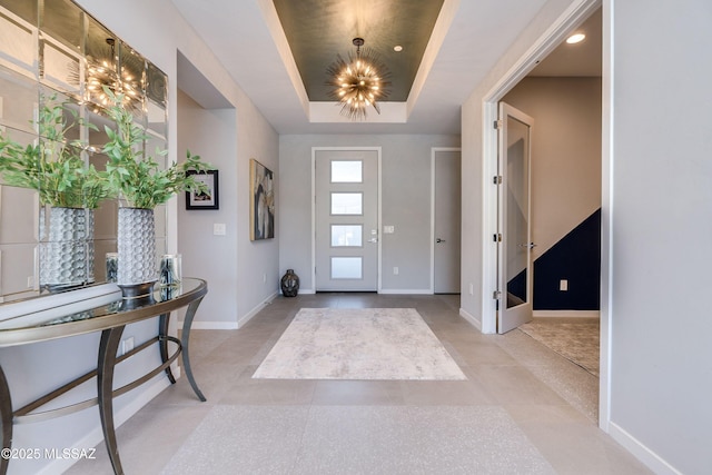 foyer entrance with a raised ceiling and a chandelier