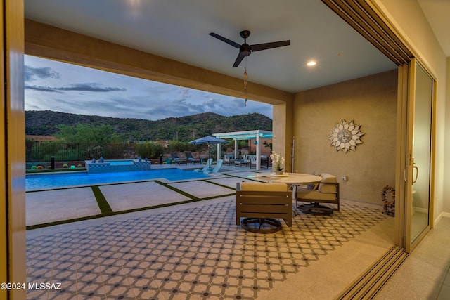 pool at dusk featuring a pergola, an in ground hot tub, a mountain view, and a patio