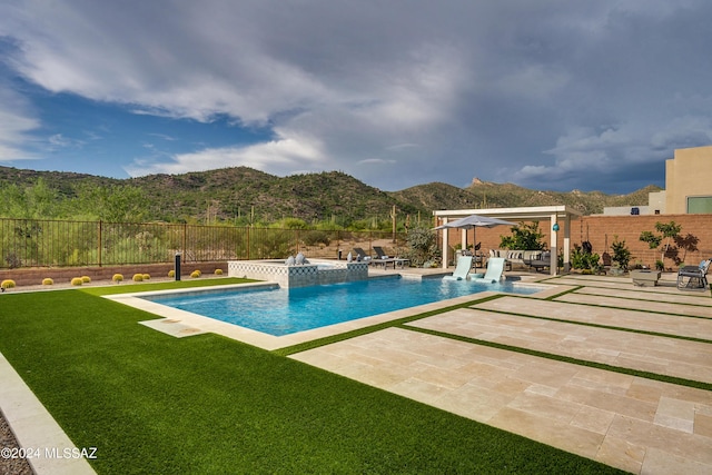 view of swimming pool featuring a mountain view, a jacuzzi, a patio area, and a lawn