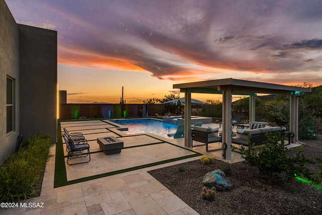 pool at dusk with an outdoor living space, a patio, and an in ground hot tub