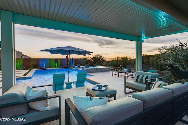 pool at dusk featuring an outdoor living space, a patio area, and an in ground hot tub