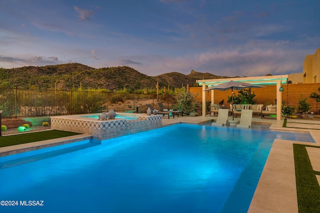 pool at dusk with a mountain view, an outdoor living space, an in ground hot tub, and a patio