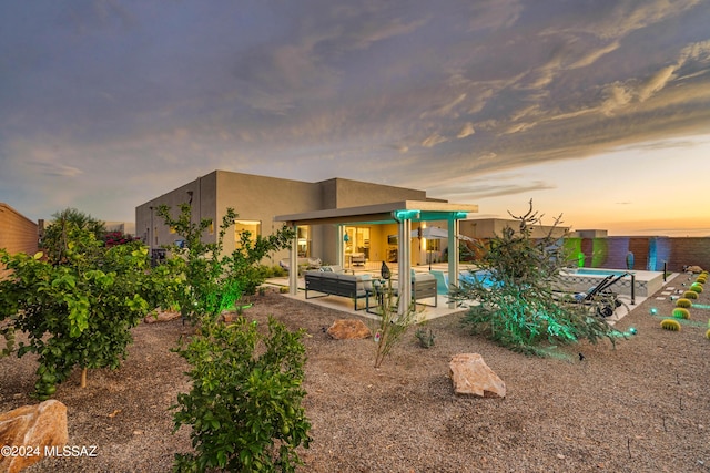 back house at dusk featuring a patio area and an outdoor hangout area