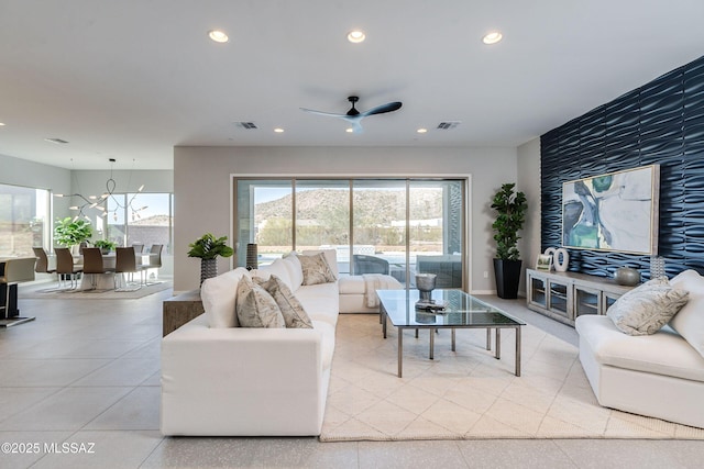 tiled living room featuring ceiling fan with notable chandelier