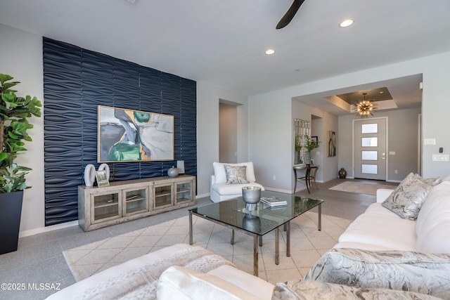 living room with ceiling fan and a tray ceiling