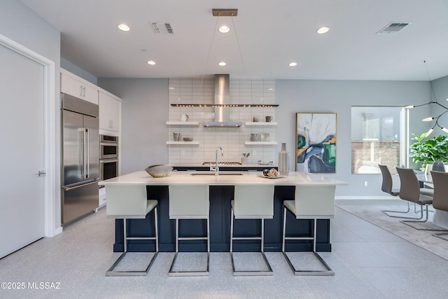 kitchen with white cabinetry, a breakfast bar, an island with sink, and stainless steel appliances