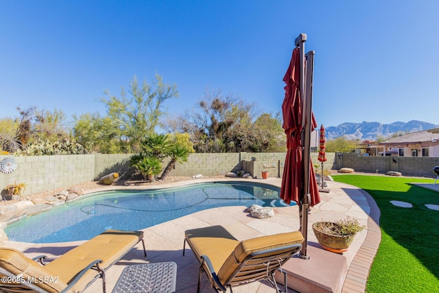 view of swimming pool with a patio, a lawn, and a mountain view