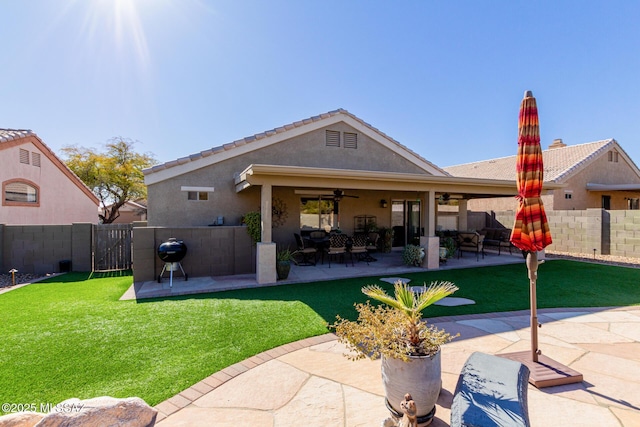 back of property with ceiling fan, a lawn, and a patio area