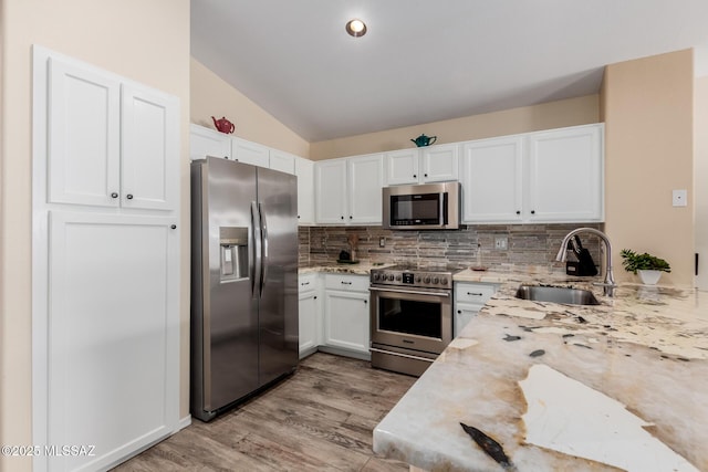 kitchen with stainless steel appliances, white cabinetry, sink, and tasteful backsplash