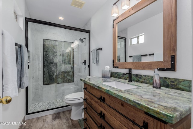 bathroom with toilet, hardwood / wood-style flooring, walk in shower, and vanity