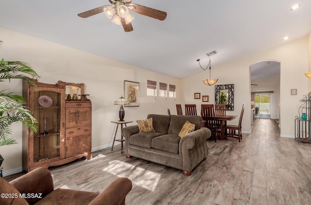 living room featuring wood-type flooring, ceiling fan, and vaulted ceiling