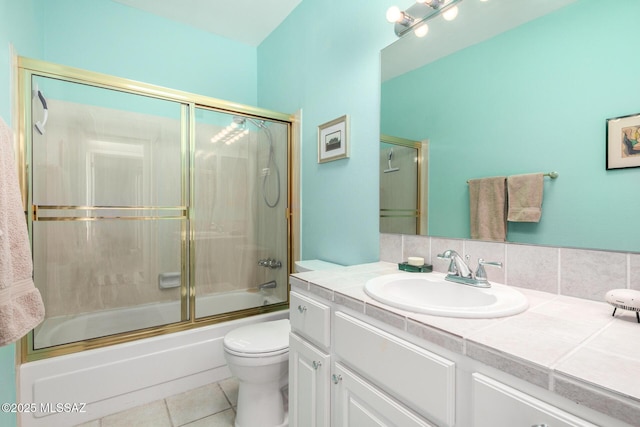 full bathroom with tile patterned flooring, shower / bath combination with glass door, toilet, backsplash, and vanity