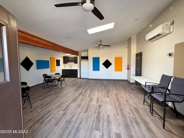 living area with an AC wall unit, light hardwood / wood-style flooring, lofted ceiling, ceiling fan, and sink