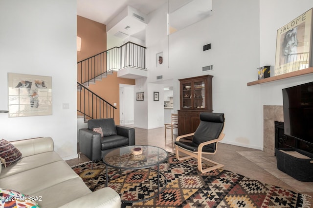 living room with a high ceiling, a tiled fireplace, and carpet