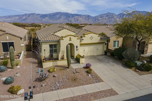 mediterranean / spanish-style house featuring stucco siding, driveway, a mountain view, an attached garage, and a tiled roof