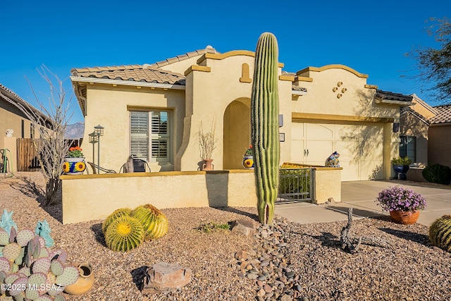 mediterranean / spanish house featuring stucco siding, driveway, a tile roof, fence, and a garage