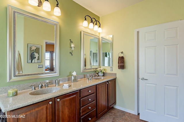 bathroom with double vanity, tile patterned flooring, baseboards, and a sink