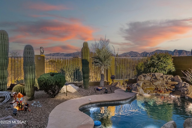 pool at dusk featuring a fenced in pool, a mountain view, and fence