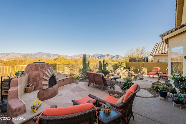 view of patio / terrace featuring an outdoor living space, a mountain view, and fence