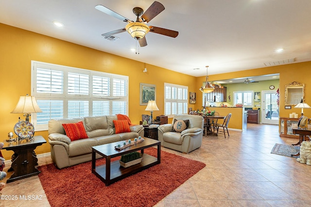 living area with light tile patterned floors, baseboards, visible vents, and ceiling fan