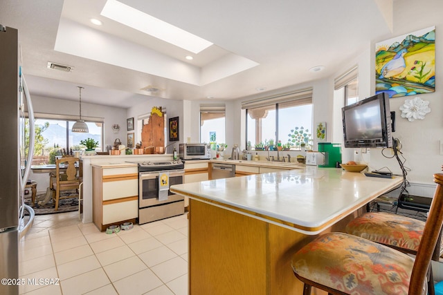 kitchen with stainless steel appliances, a skylight, a kitchen breakfast bar, and kitchen peninsula