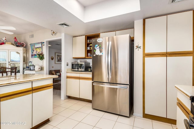 kitchen featuring ceiling fan, light tile patterned floors, stainless steel appliances, and white cabinets