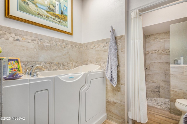 bathroom with tile walls, hardwood / wood-style floors, toilet, and separate shower and tub