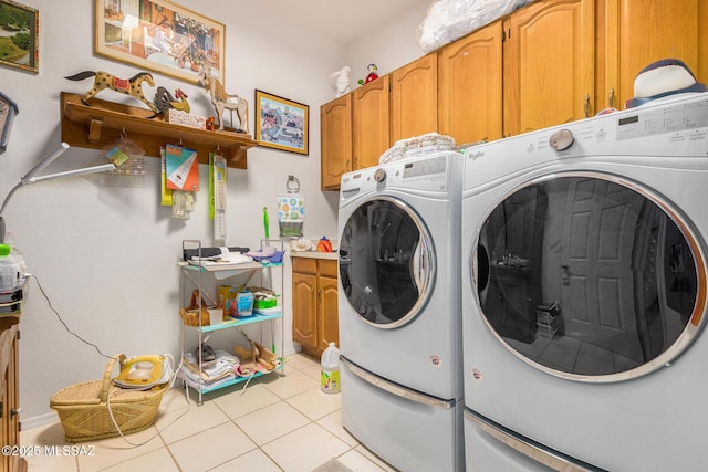 laundry area with light tile patterned floors, washing machine and dryer, and cabinets