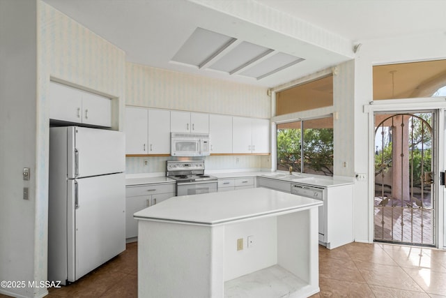 kitchen with a center island, appliances with stainless steel finishes, white cabinetry, sink, and tile patterned floors