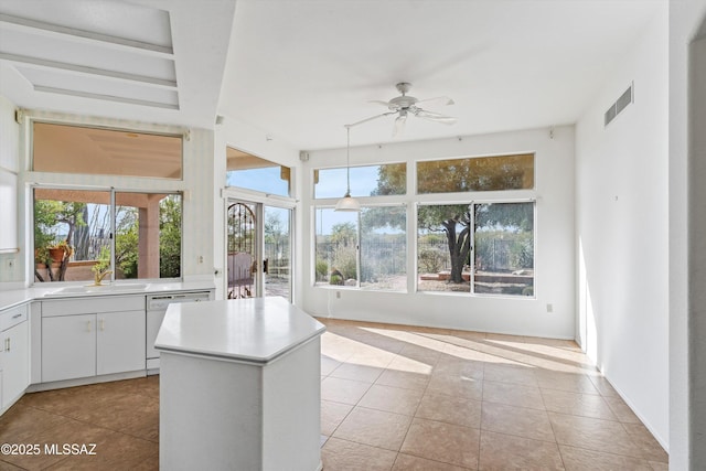 unfurnished sunroom featuring sink, ceiling fan, and a healthy amount of sunlight