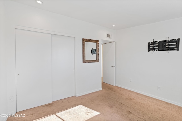 unfurnished bedroom featuring a closet and light carpet