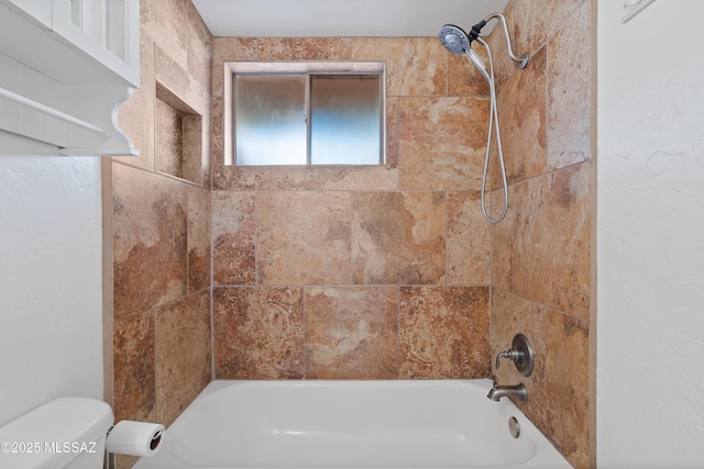 bathroom featuring toilet and tiled shower / bath