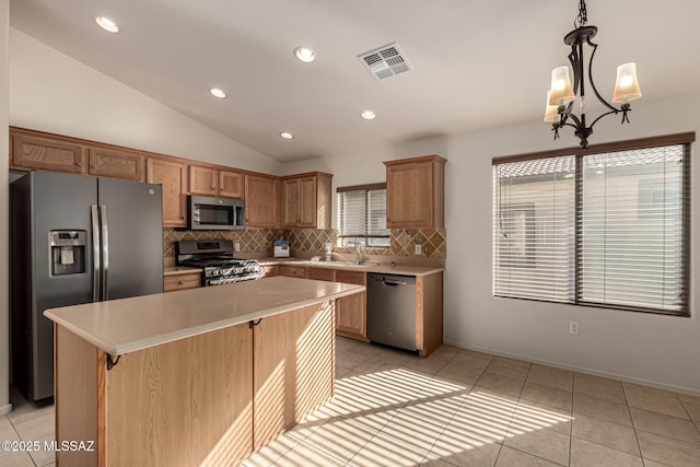 kitchen featuring vaulted ceiling, hanging light fixtures, a center island, an inviting chandelier, and appliances with stainless steel finishes