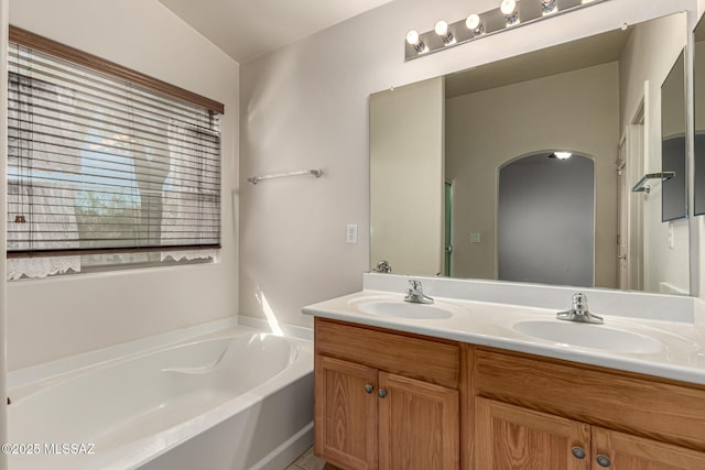 bathroom with vaulted ceiling, a bathtub, a healthy amount of sunlight, and vanity