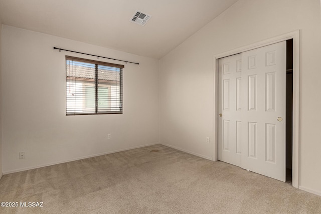 unfurnished bedroom featuring lofted ceiling, a closet, and light carpet