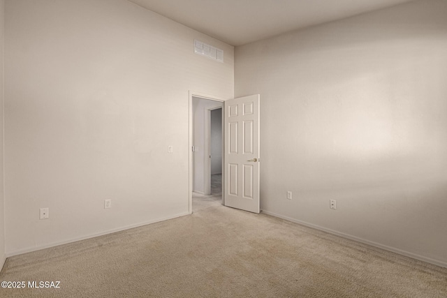 empty room featuring a towering ceiling and light carpet