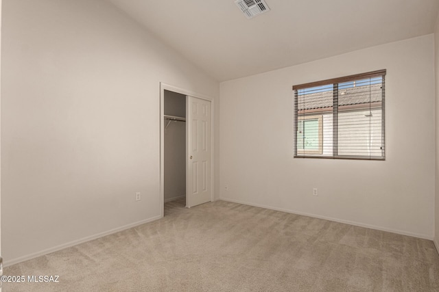 unfurnished bedroom with light carpet, a closet, and vaulted ceiling