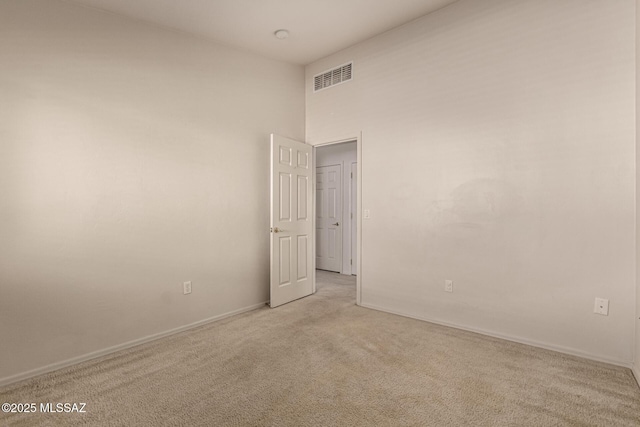 carpeted empty room featuring a high ceiling