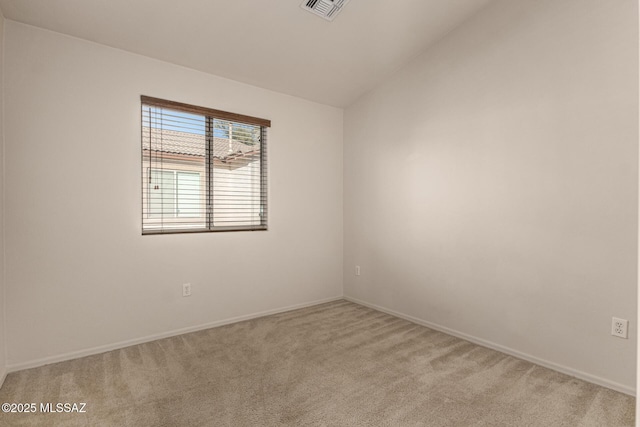 spare room featuring vaulted ceiling and light colored carpet