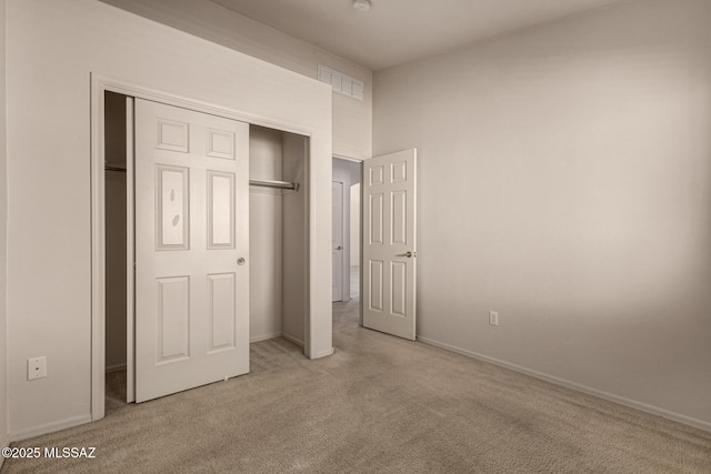 unfurnished bedroom featuring light colored carpet and a closet