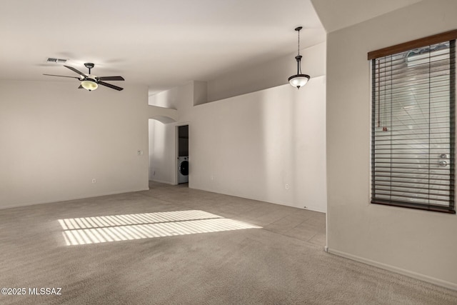 carpeted spare room featuring washer / dryer and ceiling fan