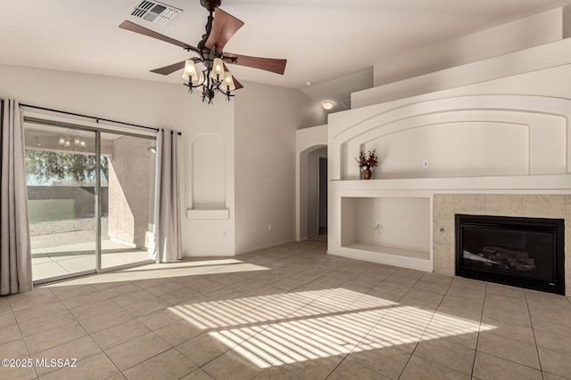 unfurnished living room featuring vaulted ceiling, light tile patterned floors, built in shelves, a tiled fireplace, and ceiling fan