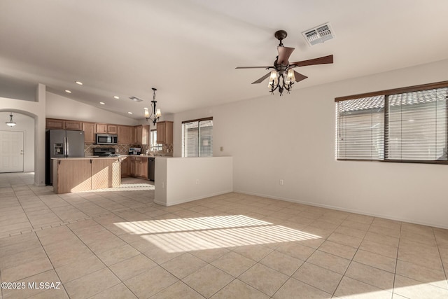 unfurnished living room featuring plenty of natural light, vaulted ceiling, light tile patterned flooring, and ceiling fan with notable chandelier