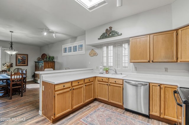 kitchen featuring hardwood / wood-style flooring, kitchen peninsula, appliances with stainless steel finishes, decorative light fixtures, and sink