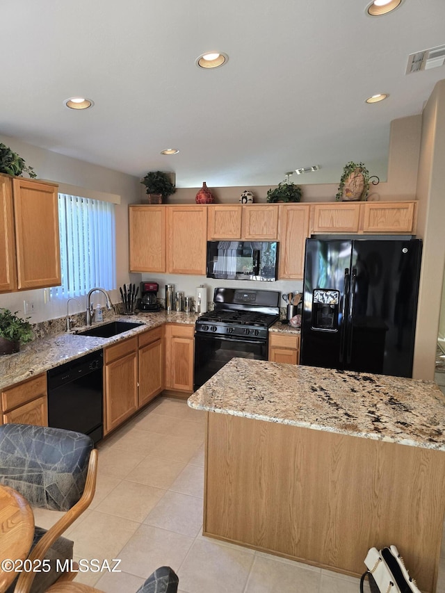 kitchen with black appliances, light tile patterned floors, light stone countertops, and sink