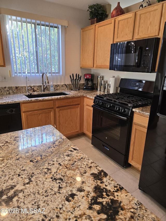 kitchen featuring light stone counters, sink, black appliances, and light tile patterned flooring