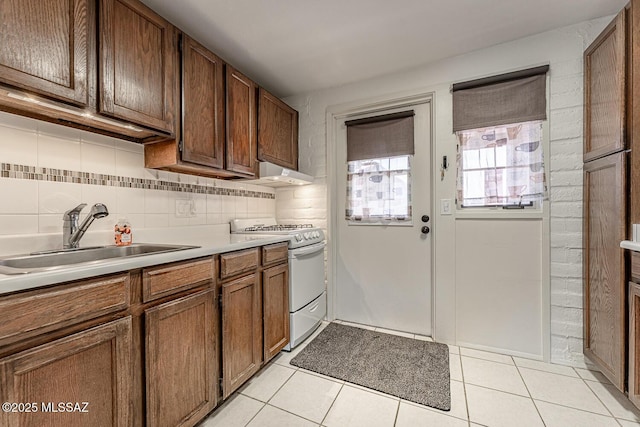 kitchen featuring light tile patterned floors, white range with gas cooktop, decorative backsplash, and sink