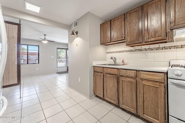 kitchen with white range with gas stovetop, ceiling fan, decorative backsplash, sink, and light tile patterned flooring