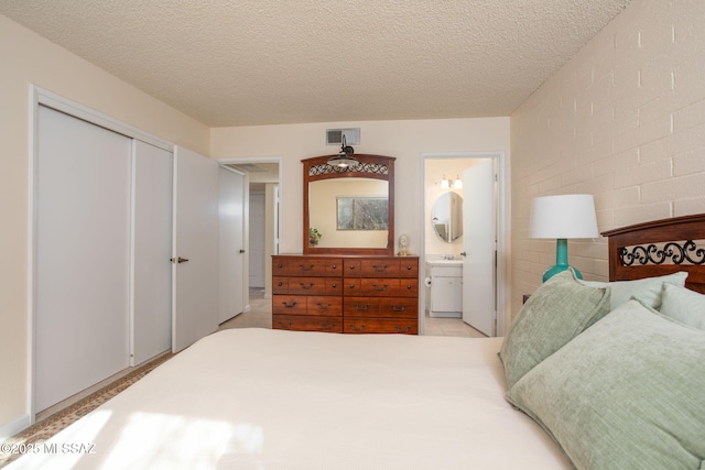 bedroom with connected bathroom, a textured ceiling, and a closet