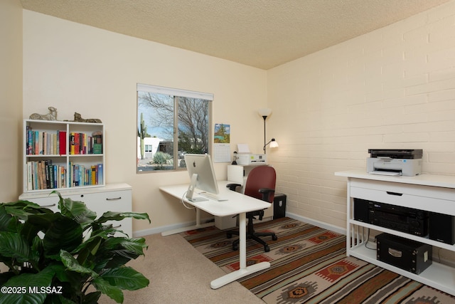 home office with brick wall, carpet floors, and a textured ceiling